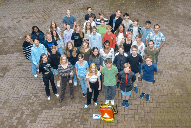Gruppe von Menschen steht dicht beieinander auf einem gepflasterten Boden, von oben fotografiert.