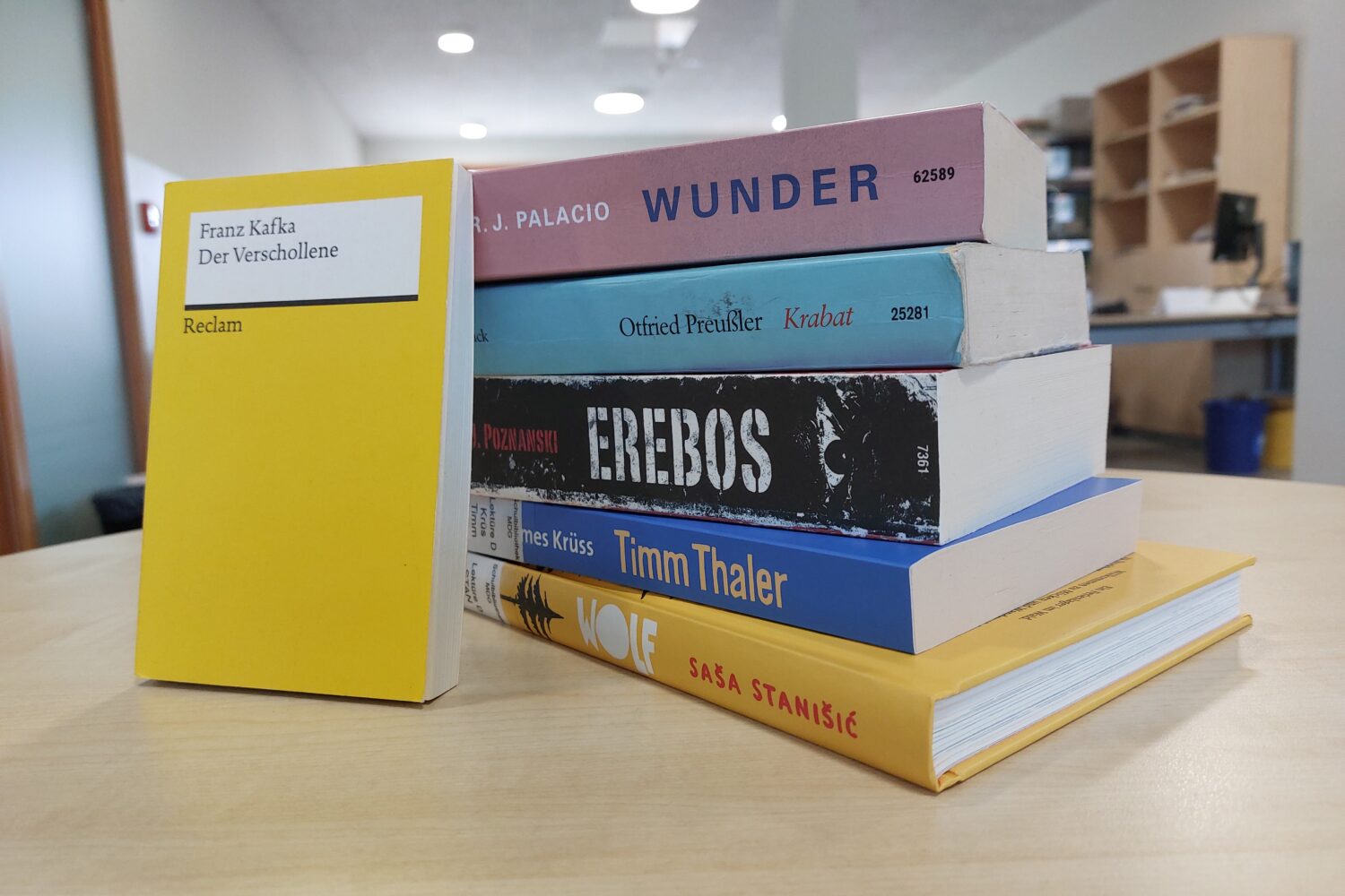 Stapel von Büchern auf Tisch; vorne steht Der Verschollene von Franz Kafka.