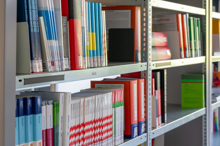 Regale voller Bücher in einer Bibliothek, geordnet nach Farben und Themen.