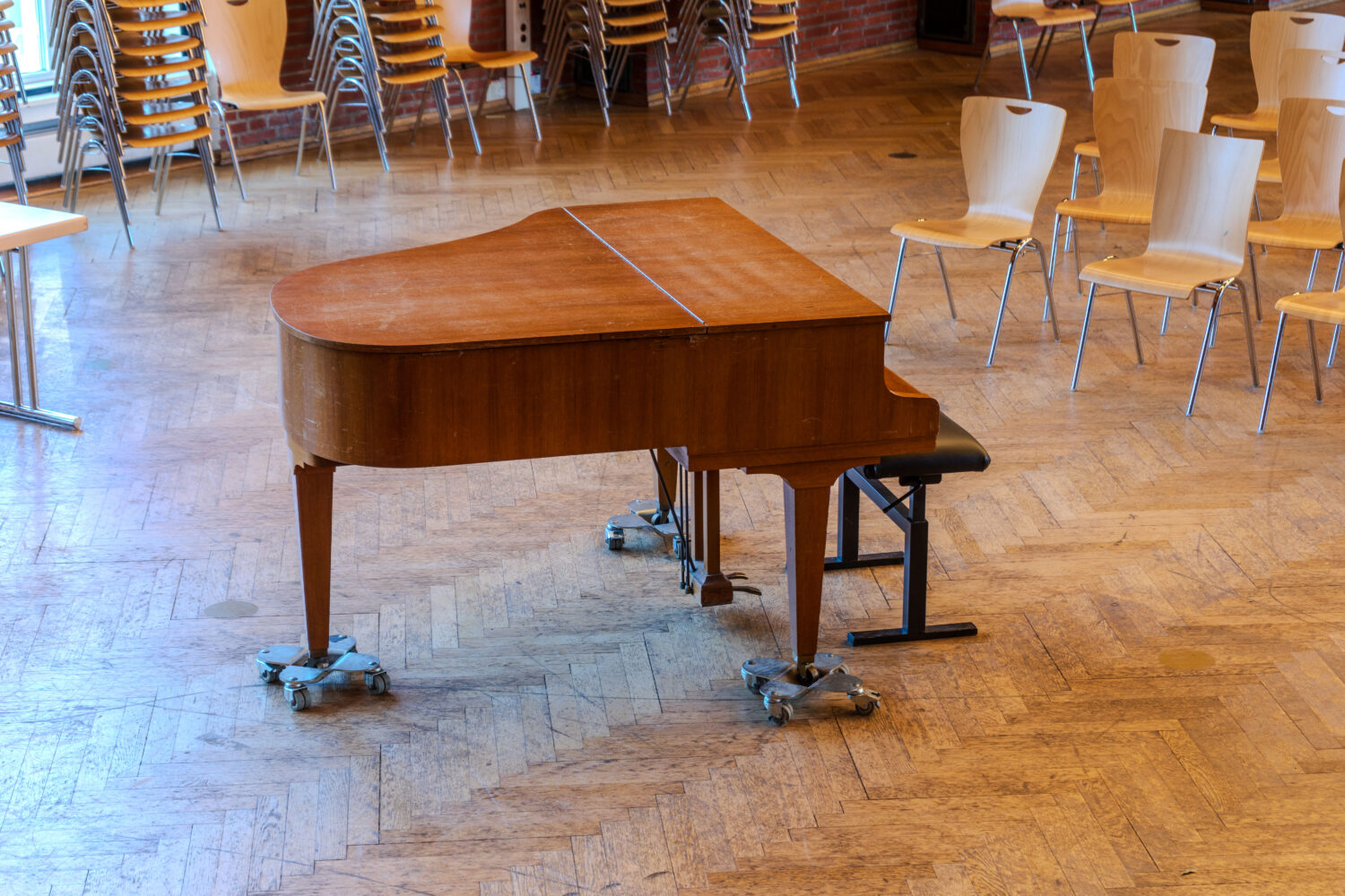 Flügel in teurem Konzertsaal mit klappbaren Holzstühlen in der Umgebung.