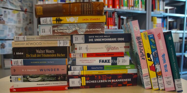 Ein Stapel gemischter Bücher auf einem Tisch in einer Bibliothek.
