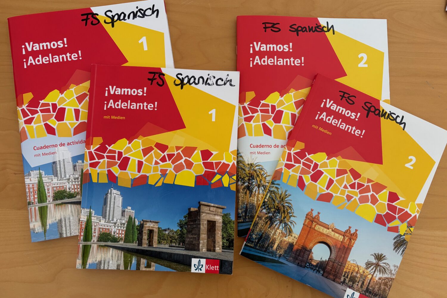 Vier Spanisch-Lehrbücher ¡Vamos! ¡Adelante! liegen auf einem Tisch.
