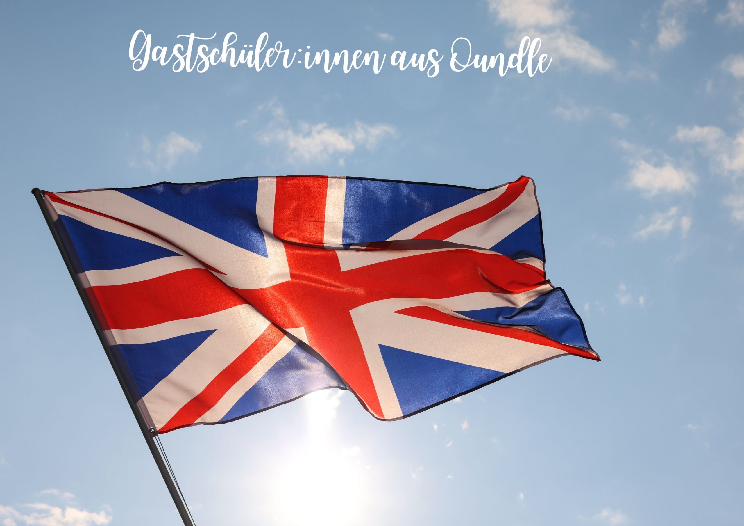Ein auf einem Mast wehendes Union Jack vor blauem Himmel mit Sonnenlicht im Hintergrund.