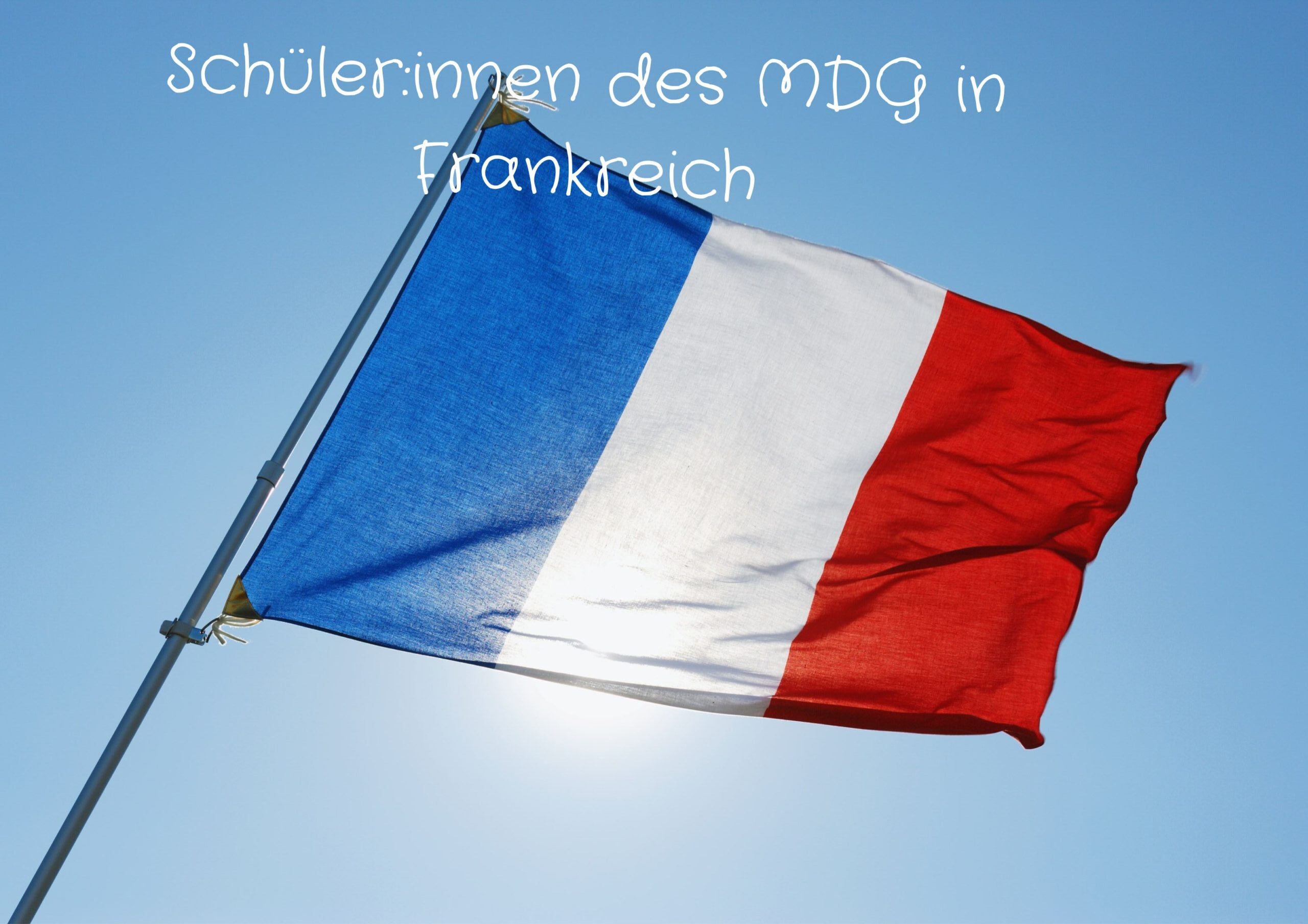 Eine französische Flagge weht vor einem strahlend blauen Himmel.