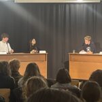 Diskussionstisch mit mehreren jungen Menschen, die auf ein Publikum blicken.