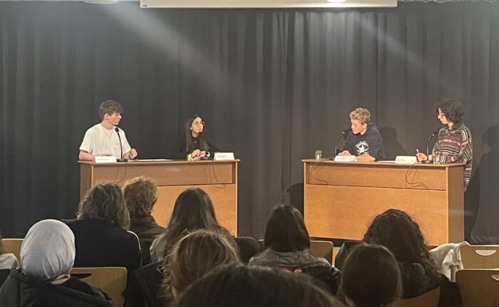 Diskussionstisch mit mehreren jungen Menschen, die auf ein Publikum blicken.