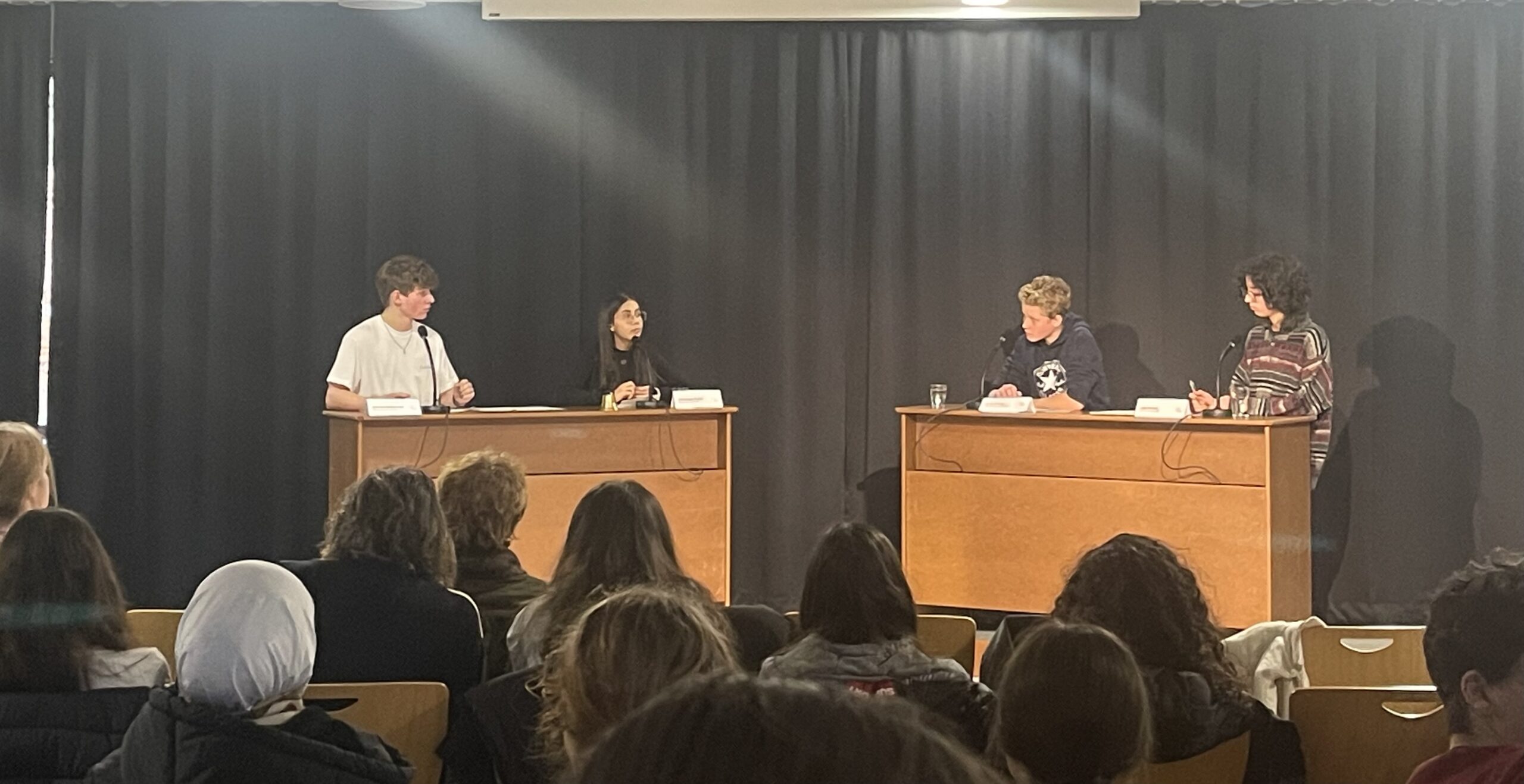 Diskussionstisch mit mehreren jungen Menschen, die auf ein Publikum blicken.