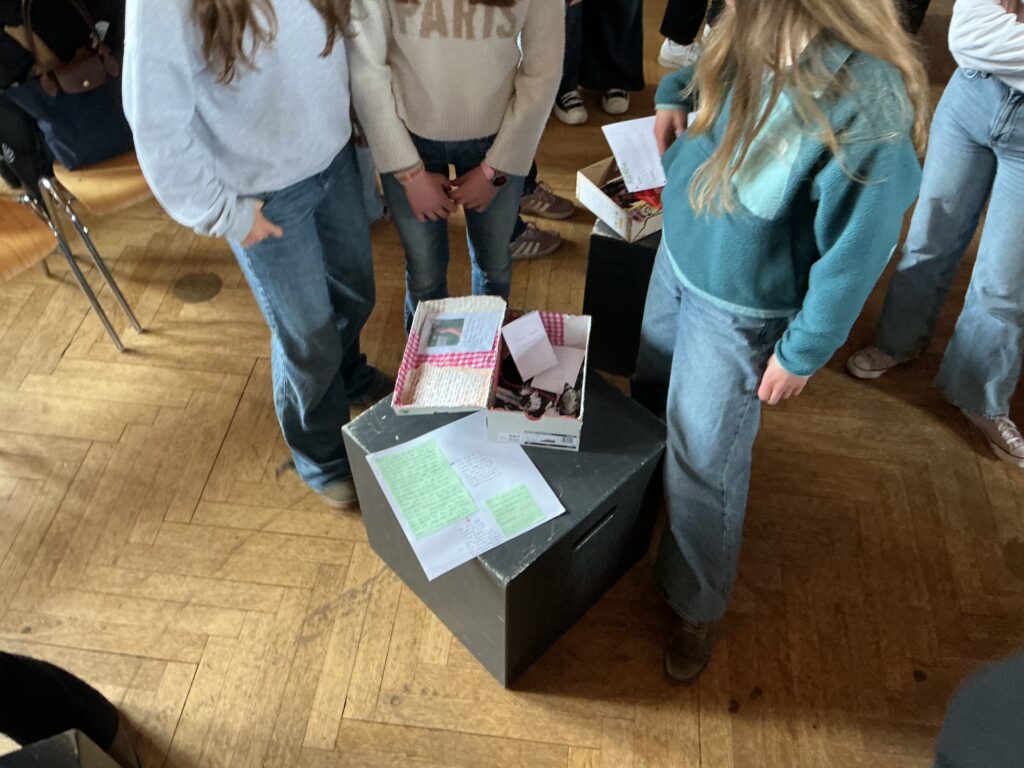 Zwei Personen mit langen Haaren stehen um einen Tisch mit Boxen und Notizen.