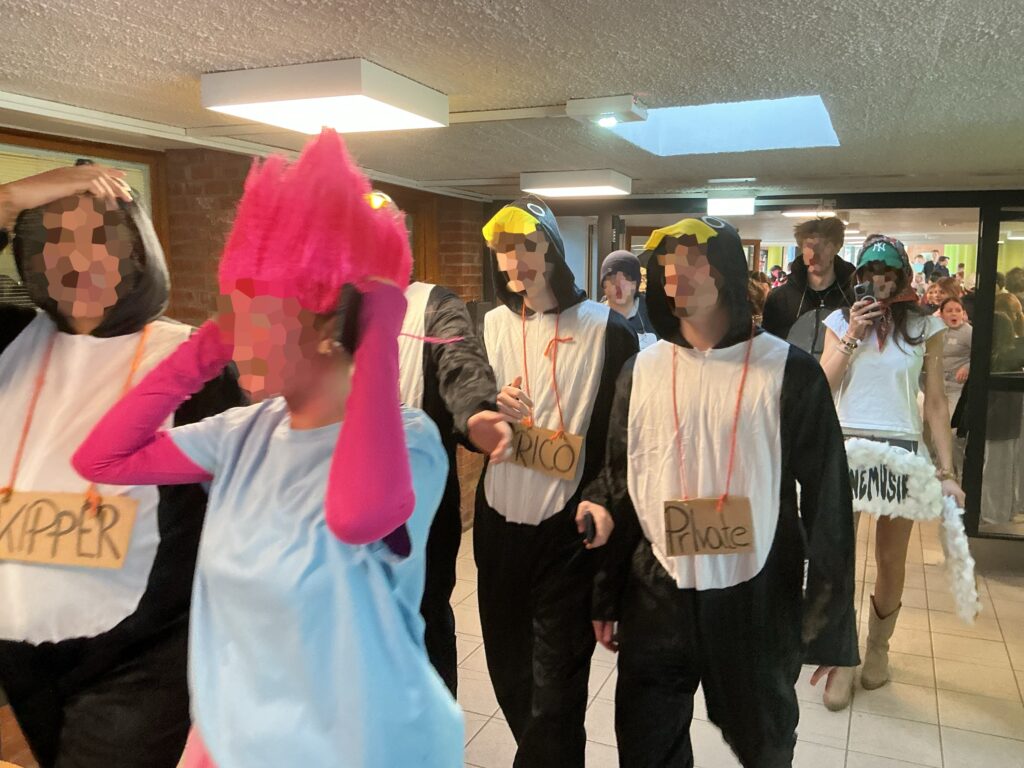 Eine Person mit pinkem Haarschmuck und pinken Ärmeln telefoniert und steht in einer Gruppe.