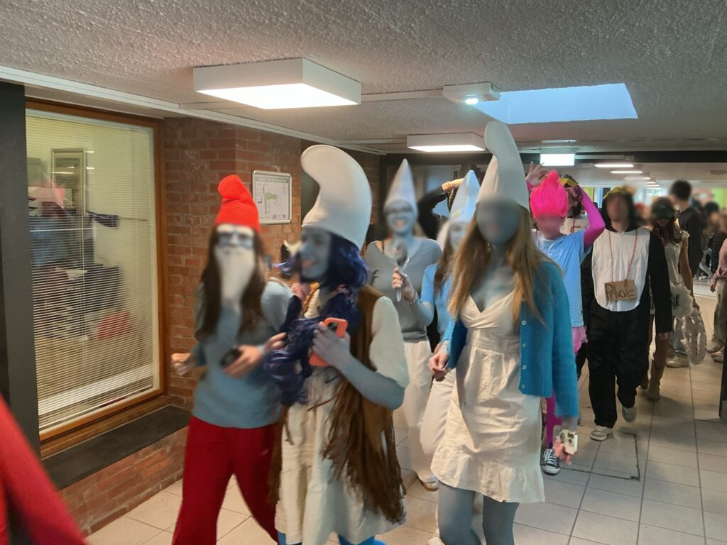 Eine Gruppe von Personen in bunten Kostümen läuft durch einen Flur.