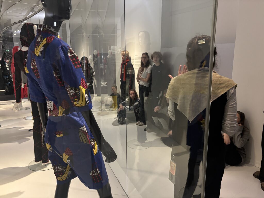 Schicke Frau mit einem bunten Kleid und einem Schal, blickt auf eine Ausstellung.