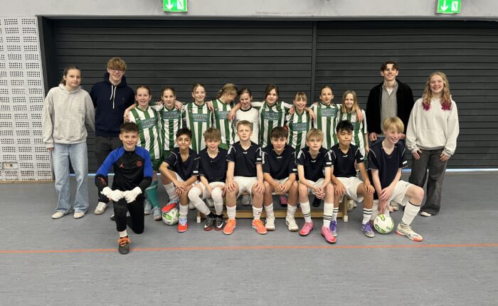Gruppenscreenshot mit Jungen und Mädchen in Sportkleidung, die fröhlich in einer Halle posieren.