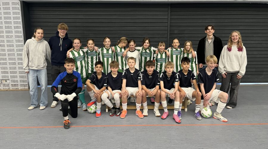 Gruppenscreenshot mit Jungen und Mädchen in Sportkleidung, die fröhlich in einer Halle posieren.