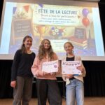 Drei Mädchen stehen auf der Bühne und halten Urkunden. Im Hintergrund eine festliche Präsentation.