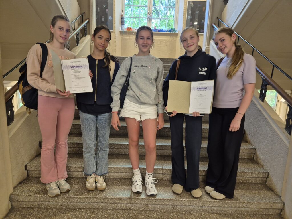 Fünf Schülerinnen des MDG stehen lächelnd auf einer Treppe und halten Urkunden in der Hand.